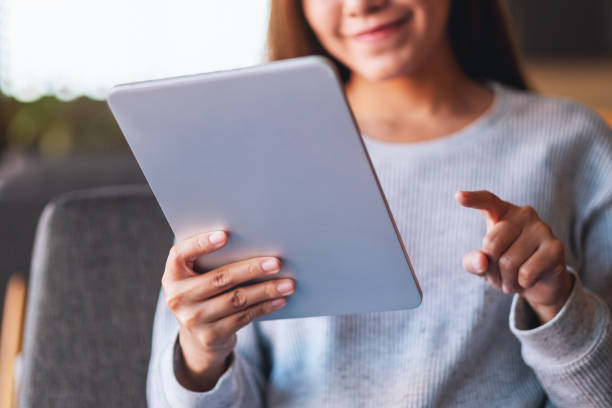 istock a beautiful young asian woman holding and using digital tablet 1295729760