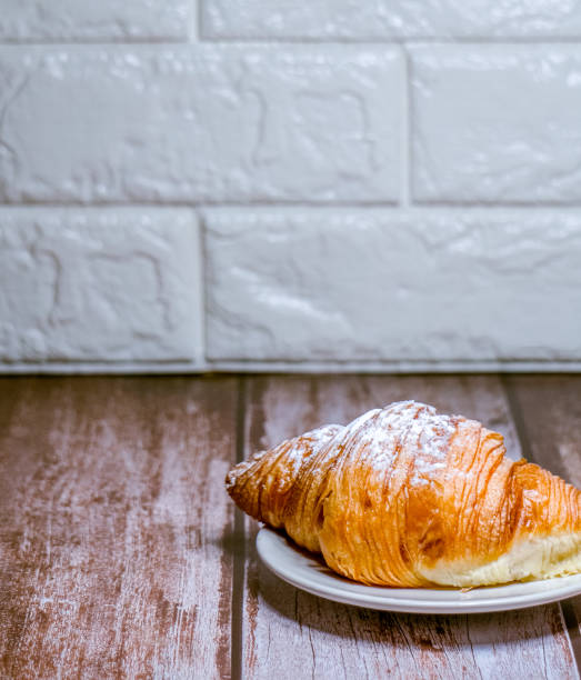 istock Croissants sprinkled with icing sugar in a white plate on a wooden table. 1295729940