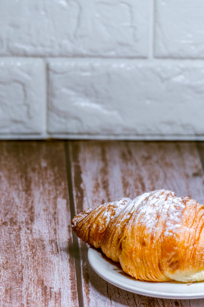 istock Croissants sprinkled with icing sugar in a white plate on a wooden table. 1295729943