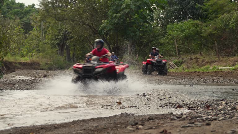 Group of tourists driving 4x4 bikes thru water in Costa Rica