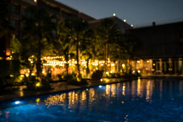Blur wedding party in garden near the pool of luxury hotel with lights bokeh at night for background usage.