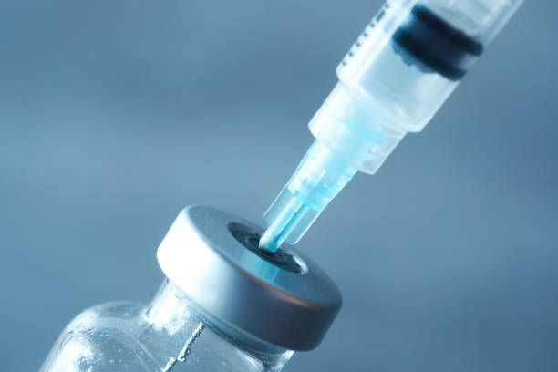 istock glass vial and syringe on black background 1295739307