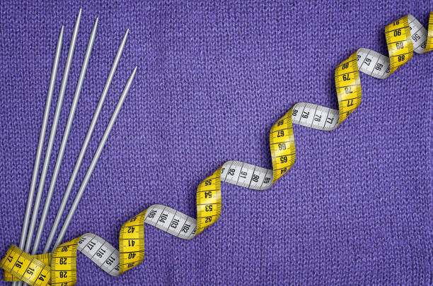 knitting needles and a yellow centimeter on a lilac knitted fabric
