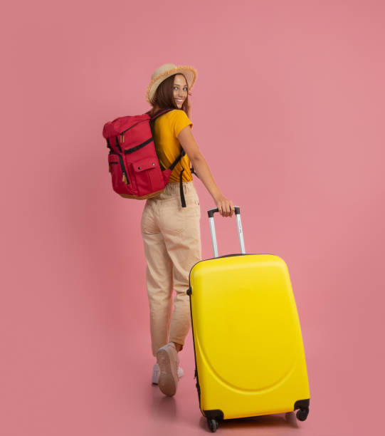 vista posteriore della donna zaino in spalla con valigia su sfondo rosa - beautiful airport women one person foto e immagini stock