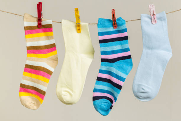 istock multicolored socks, dry after washing, hanging on a clothesline with clothespins on a light background 1295744901
