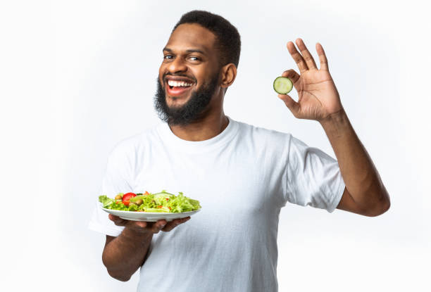 istock Joyful Black Man Holding Vegetable Salad Gesturing Okay, White Background 1295745510