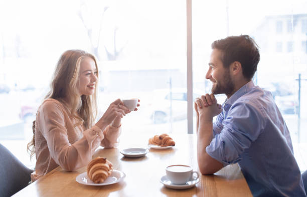 istock Affectionate young couple having brunch together at cafeteria, enjoying friendly talk near window, drinking coffee 1295745949