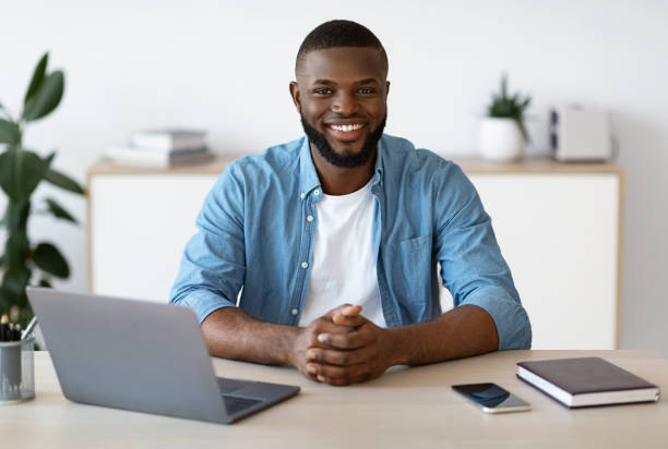 istock Young Black Freelancer Guy Sitting At Desk With Laptop At Home Office 1295745954