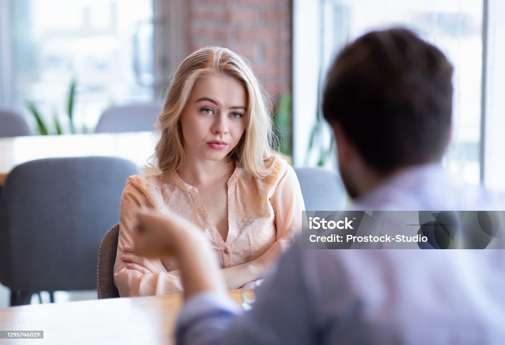 Bad date. Young woman feeling bored during dinner at cafe, unhappy with her boyfriend, disinterested in conversation Bad date. Young woman feeling bored during dinner at cafe, unhappy with her boyfriend, disinterested in conversation. Stressed couple having difficulties in relationship, arguing in coffee shop Dating Stock Photo
