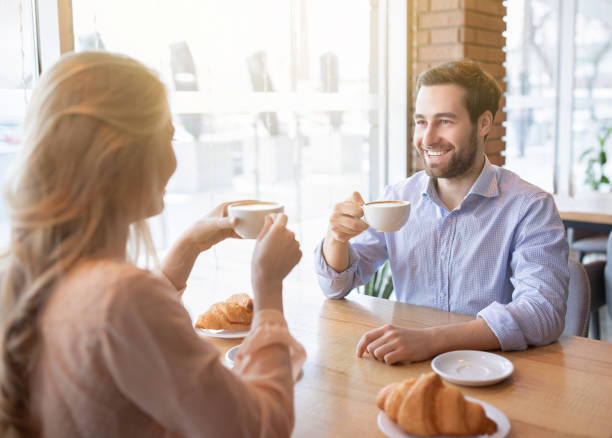 istock Cheerful young guy having coffee together with his girlfriend at cafe, chatting and smiling during breakfast 1295746556