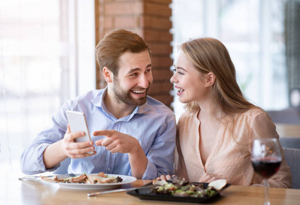 istock Happy young spouses checking their smartphone during romantic dinner at restaurant 1295746610