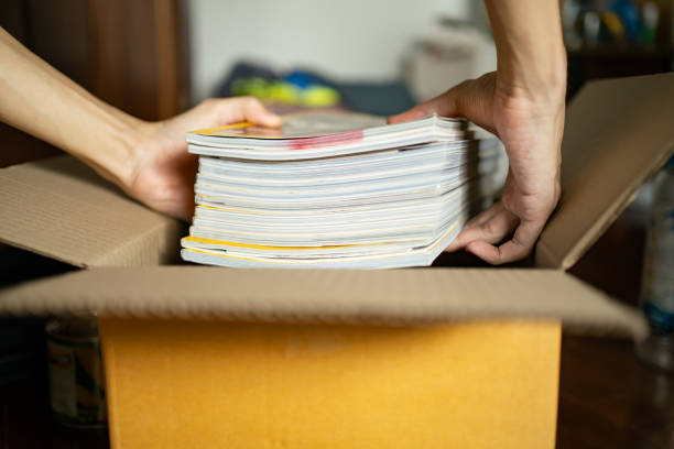 Putting old magazines into a cardboard box