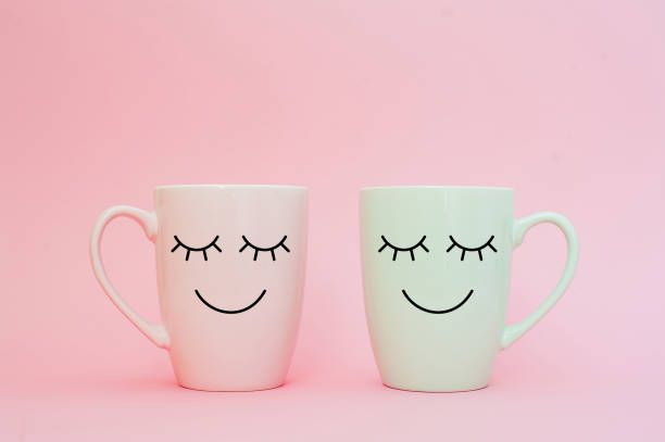Happy friday word. Two cups of coffee stand together to be heart shape on pink background with smile face on cup. Concept about love and relationship. Creative colorful greeting card stock photo