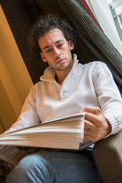 istock young man reading the newspaper on an armchair 1295750057