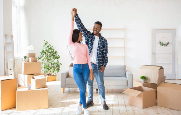 istock Affectionate black couple dancing in their new apartment among cardboard boxes on relocation day, panorama 1295750207