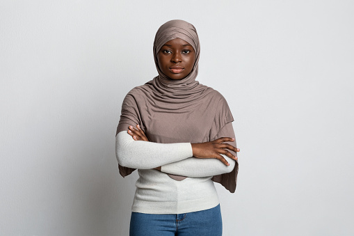 Serious Black Muslim Woman Standing With Folded Arms Over Light Background, Confident African Islamic Lady Posing In Studio, Religious Millennial Female In Headscarf Looking At Camera, Copy Space