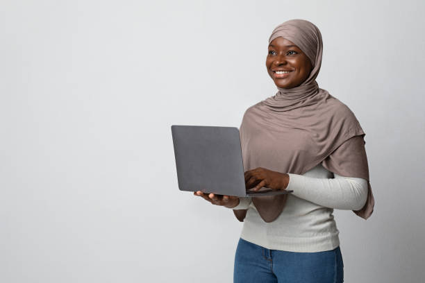 istock Thoughtful Black Muslim Woman With Laptop In Hands Over Light Studio Background 1295752621