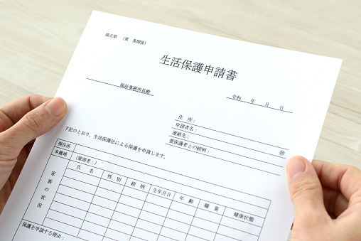 Human's hands having Japanese public assistance application form