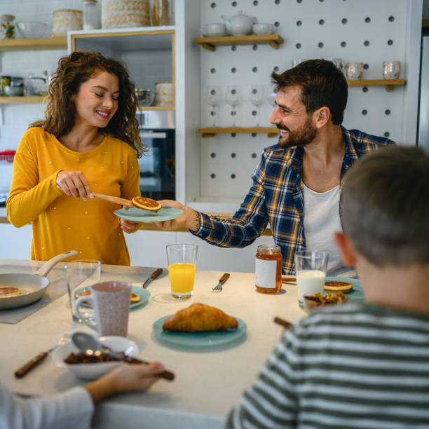 istock Young happy family communicating while having breakfast in the kitchen 1295756631