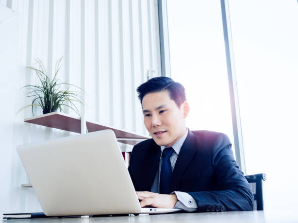 istock Asian handsome businessman in suit working with laptop computer on desk in office. 1295758740