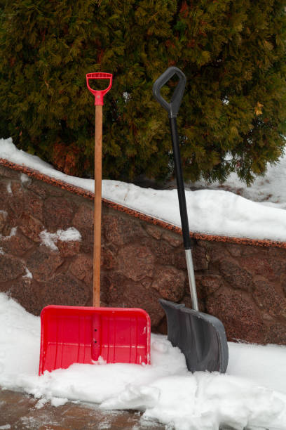istock Two plastic snow shovels stand in front of  fence 1295759110