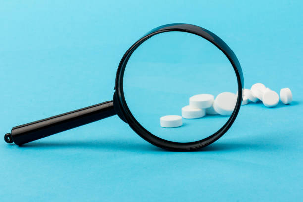istock Concept - pharmaceutical testing, testing of medicines, magnifying glass, tablets on a blue background. Doping control. 1295759154