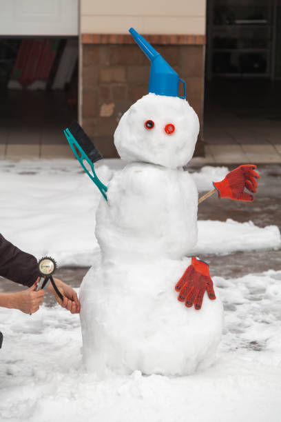 istock Funny snowman stands in front of garage 1295759211