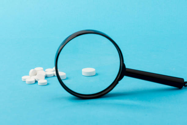 istock Concept - pharmaceutical testing, testing of medicines, magnifying glass, tablets on a blue background. Doping control. 1295759310