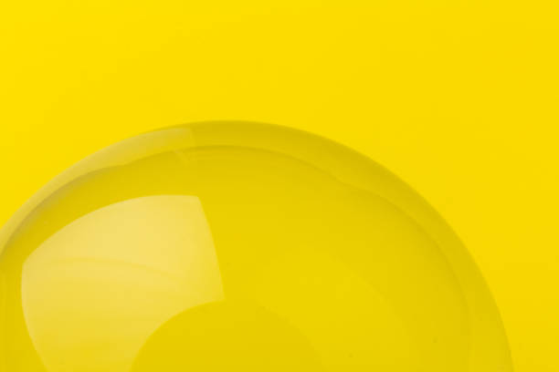Crystal, transparent ball, sphere on a yellow background.