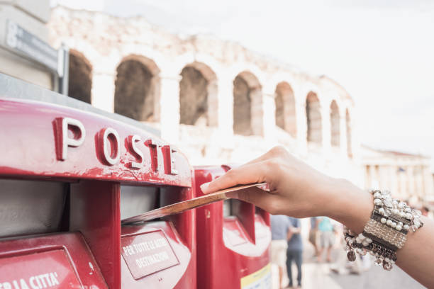 Young women discovering Italy-Verona, sending postcard in public mailbox