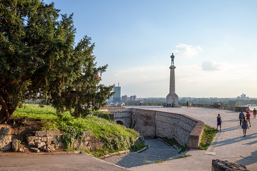 Picture of the iconic victory statue seen on Belgrade's fortress, Kalemegdan, with a group of tourists standing in front of it. Also known as Pobednik, or Viktor, This statue is one of the symbols of Belgrade, Serbia