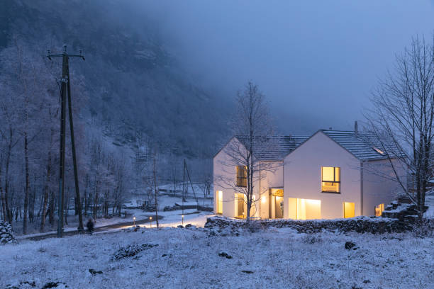 山、雪、木々に覆われた明るい窓が備えたモダンな白い家。チルストマスムード - wood window ストックフォトと画像