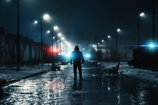Man silhouette in misty alley at night city park, mystery and horror foggy cityscape atmosphere, alone stalker or crime person stock photo