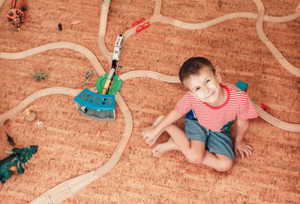Child plays with wooden railway road in his room, lifestyle Child plays with wooden railway road in his room, top view cork material stock pictures, royalty-free photos & images
