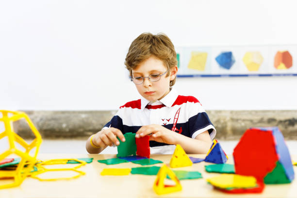 istock Happy kid boy with glasses having fun with building and creating geometric figures, learning mathematics and geometry 1295764934