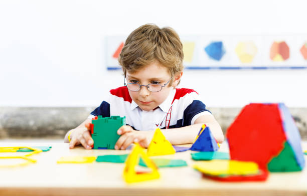 istock Happy kid boy with glasses having fun with building and creating geometric figures, learning mathematics and geometry 1295764991