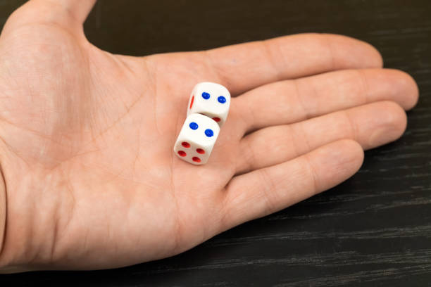 dadi con punti blu nella mano di un uomo da vicino su uno sfondo nero - dice rolling throwing businessman foto e immagini stock