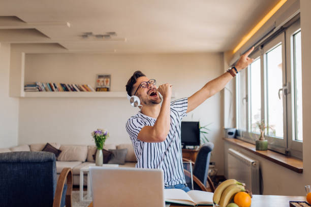 istock Young man watching an online concert, dancing and singing at home 1295768933