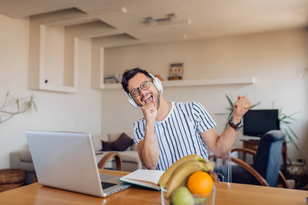 istock Young man dancing and singing after working at home 1295768936