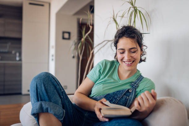 istock Happy girl enjoying while reading a book at home 1295769123