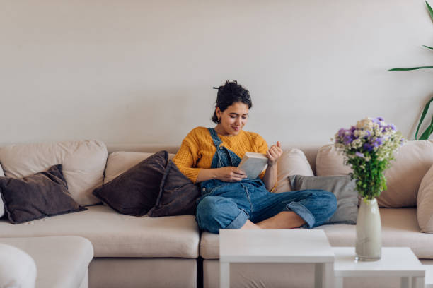Portrait of a young woman enjoying on the sofa and reading stock photo