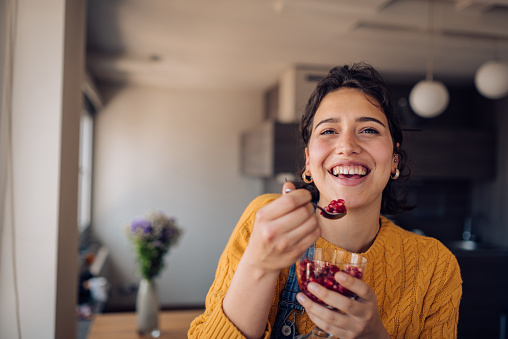 Portrait of a beautiful girl eating pomegranate and enjoying at home.