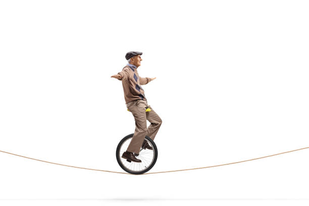 istock Elderly man riding a unicycle on a rope 1295770363