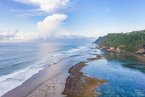 Bali rocky shores on the south Bukit. Ocean waves crashing onto coral reef. View from above.
