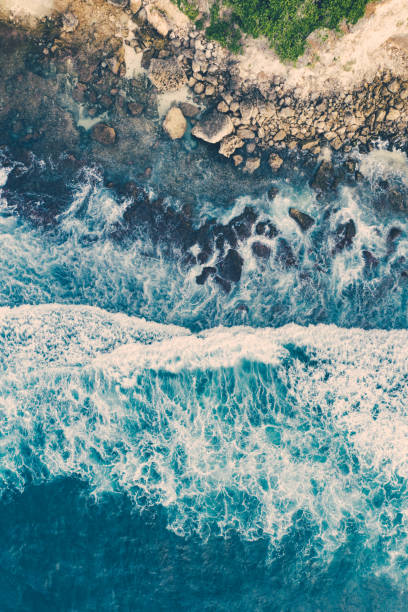 Bali, aerial shot of the blue ocean and beach full of big rocks.