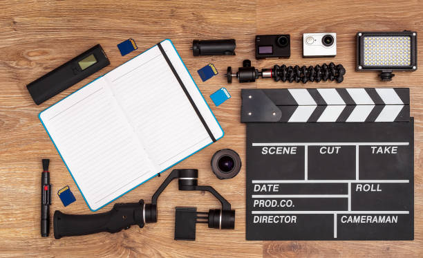 istock A set for videography and video-blogging equipment: action-cameras, clapperboard, compact LED-light, steadicam, tripods, memory cards, recorder, lens, cleaner and notepad over wooden table background. 1295771039