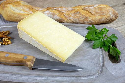 hard cantal a wooden board with baguette of bread