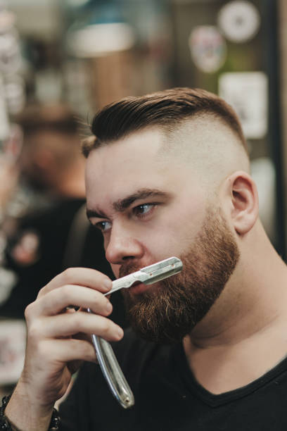 istock bearded brutal man with a straight razor 1295772267