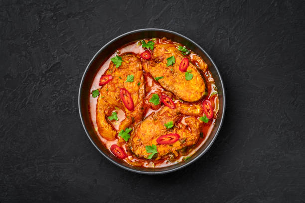 macher jhol in black bowl on dark slate table top. indian cuisine bengali fish curry. asian food and meal. top view - indian culture spice cooking herb imagens e fotografias de stock