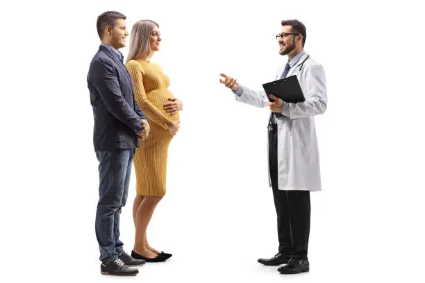 Photo of Doctor talking to a pregnant woman and a man